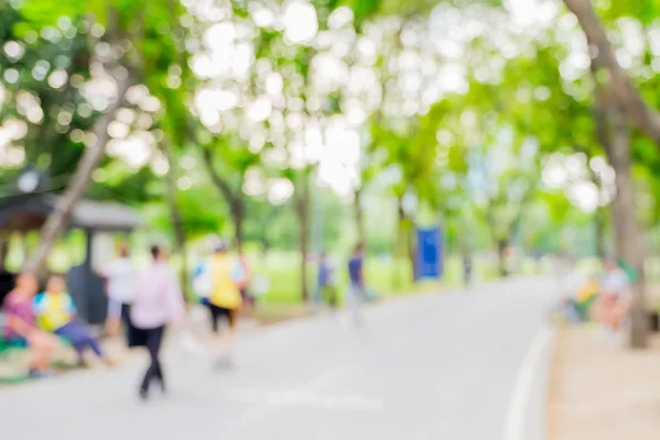 Rozmyte tło, ludzie sprawować na zielony park z bokeh ligh — Zdjęcie stockowe