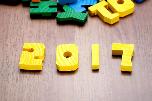 2017 Nieuwjaar nummer gele kleur speelgoed op houten tafel met andere f — Stockfoto