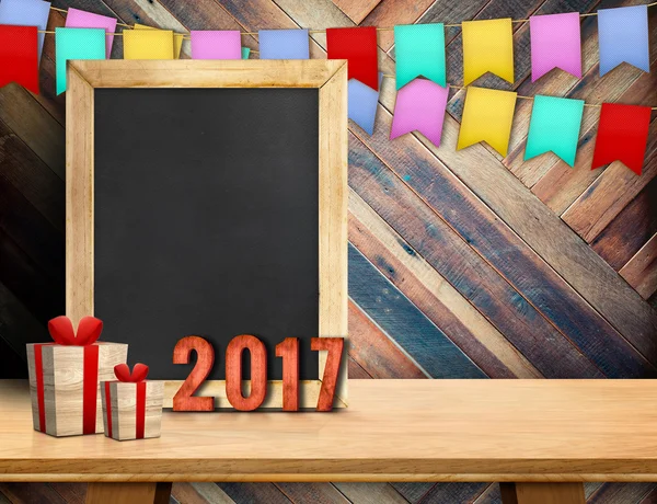Happy new year on blackboard with gift and colorful flag banner — Stock Photo, Image