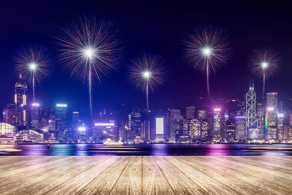 Empty wood plank floor with fireworks over cityscape at night ba