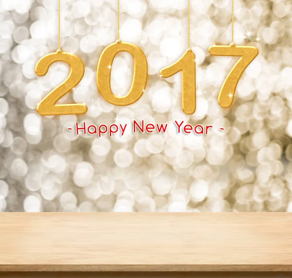 2017 new year hanging over plain wood table top with gold sparkl — Stock Photo, Image