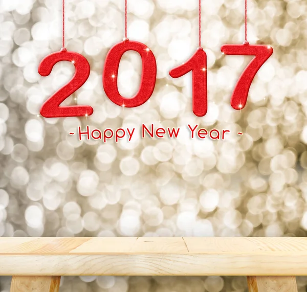 2017 new year hanging over plain wood table top with gold sparkl — Stock Photo, Image