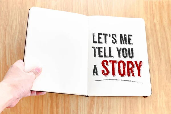 Tangan memegang notebook dengan Mari saya ceritakan sebuah kata cerita berbaring — Stok Foto