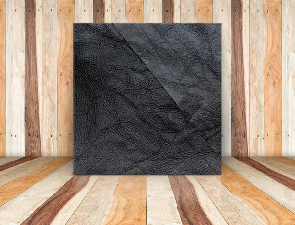 Lona cuadrada de cuero negro apoyada en el suelo y la pared de madera — Foto de Stock