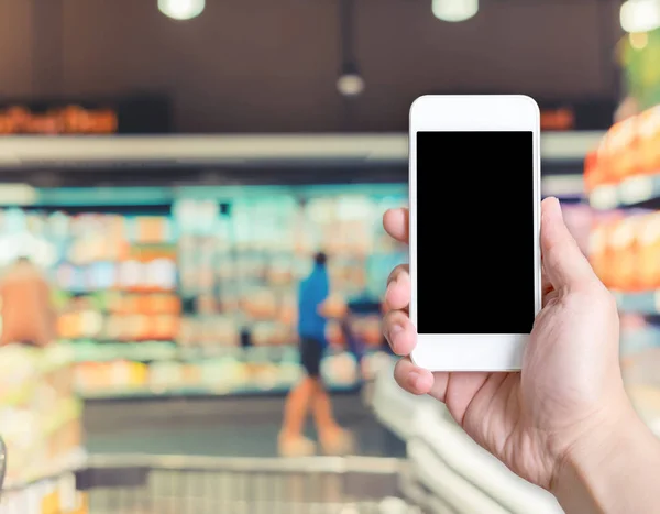Kezében mozgatható telefon-val ügyfél blur, a stor szupermarket — Stock Fotó