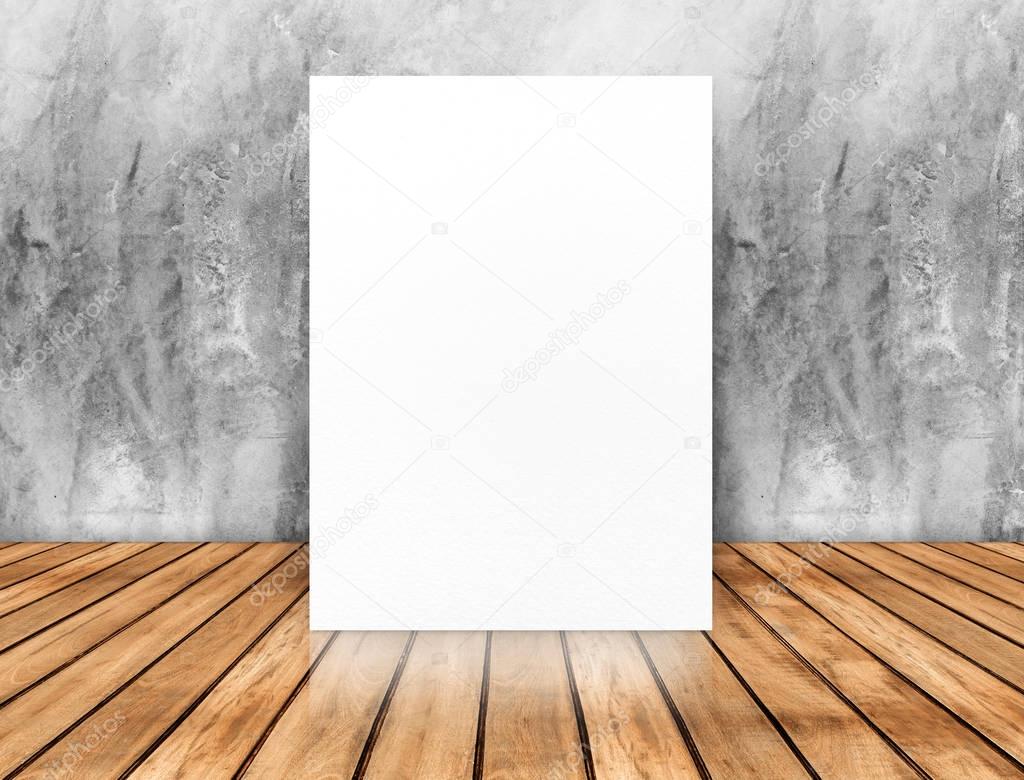 Blank white poster leaning at concrete wall on wood plank floor,