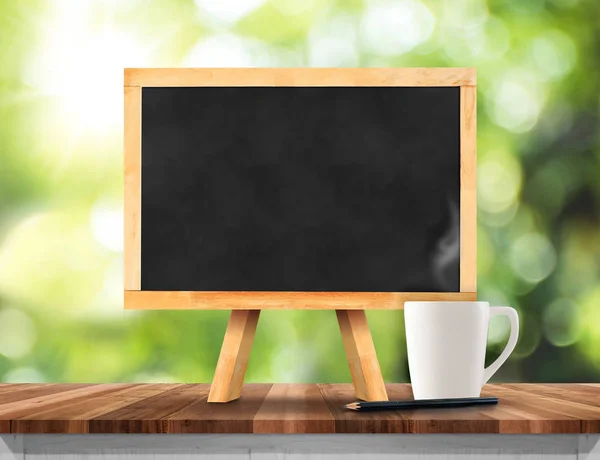 Blackboard with easel on brown wood table top with sun and blur — Stock Photo, Image