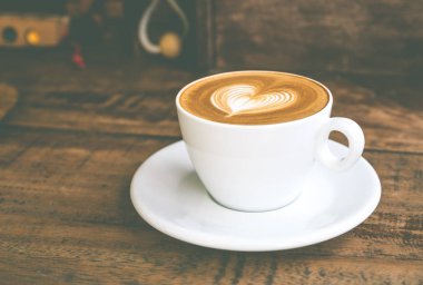 Beyaz kahve fincanı ile kalp şekli latte sanat ahşap sekmesinde yukarı kapatın