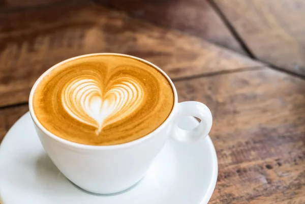 Закройте чашку белого кофе с искусством латте в форме сердца на дереве — стоковое фото