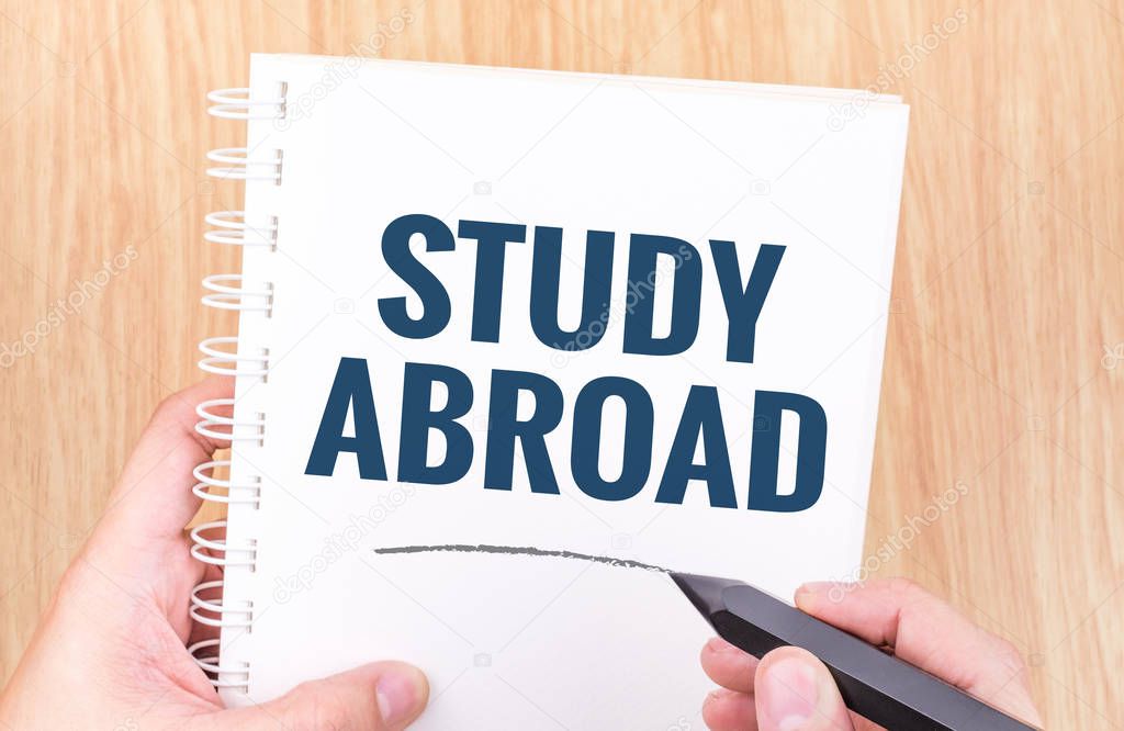 Study abroad word on white ring binder notebook with hand holdin