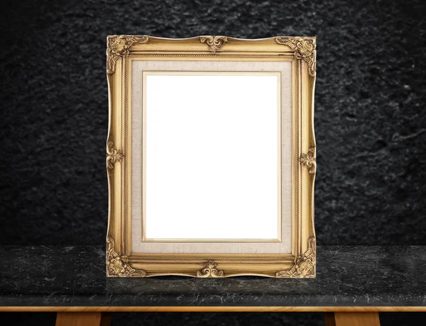 Blank Gold victorian picture frame on black marble table at dark