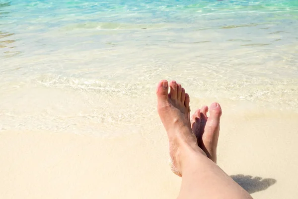 Bliska podróżnik krzyż boso nóg leżąc na plaży na morzu shor — Zdjęcie stockowe