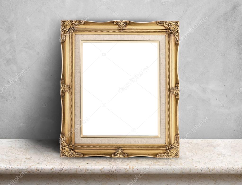 Blank Gold victorian picture frame on cream marble table at grey