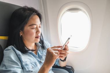 Asyalı kadın pencerede otururken uçakta koltuk ve airpl üzerinde açmak