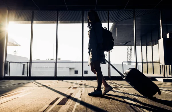 Silueta de niña caminando con equipaje caminando en el aeropuerto — Foto de Stock
