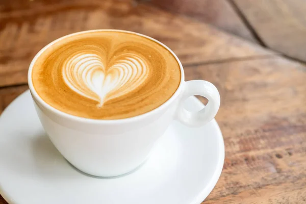 Cerrar taza de café blanco con forma de corazón arte latte en pestaña de madera — Foto de Stock