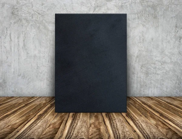 Marco de tela negra en blanco apoyado en pared de hormigón sobre madera — Foto de Stock