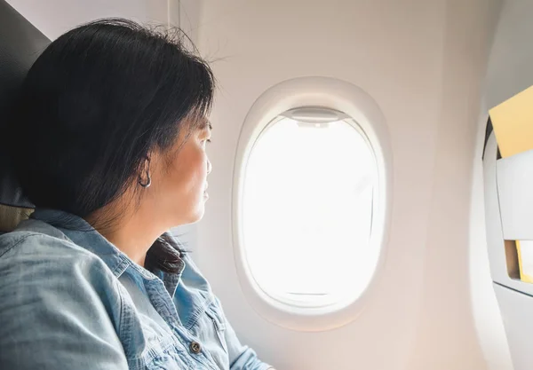 Asian Woman sitting at window seat in airplane and look outside