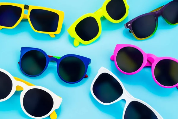 Conjunto de gafas de sol yacen en el fondo azul del estudio, cono de verano — Foto de Stock