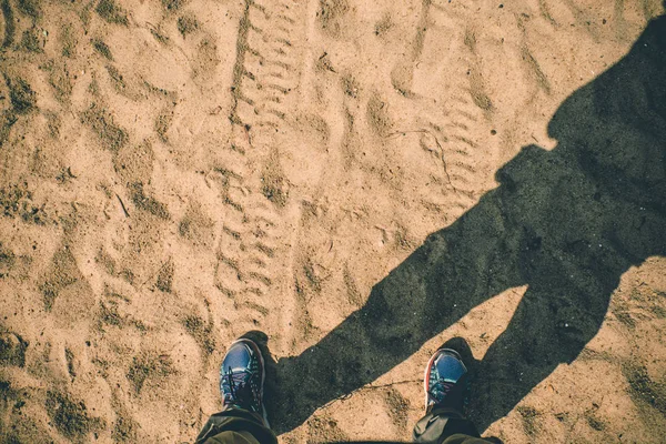 Vista aérea del zapato de pie sobre arena con huellas de neumáticos y sombra — Foto de Stock