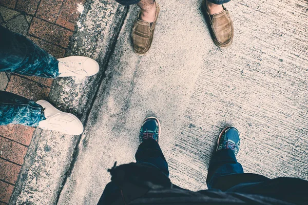 Aerial view of group of teenager feet standing on concrete stree