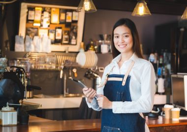 Asyalı kadın barista aşınma jean önlük tutun tablet bilgisayar kahve
