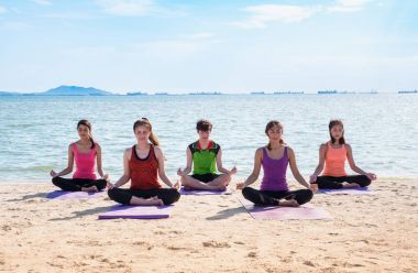 Yoga sınıf deniz Beach deki güneşli bir gün, bir grup insan lotu yapıyor