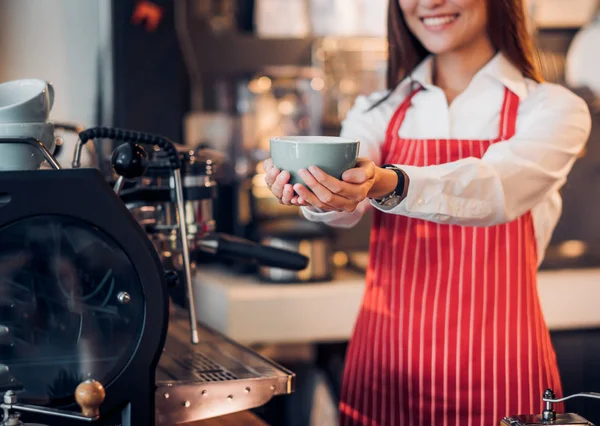 Close up mão de mulher barista desgaste avental vermelho segurando café quente — Fotografia de Stock