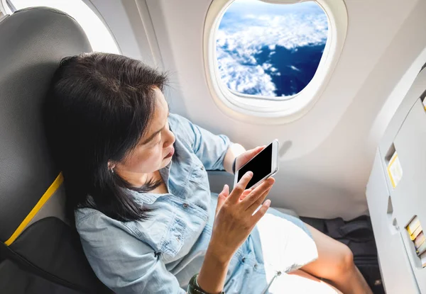 Vista superior de la mujer asiática sentada en el asiento de la ventana en avión y t — Foto de Stock