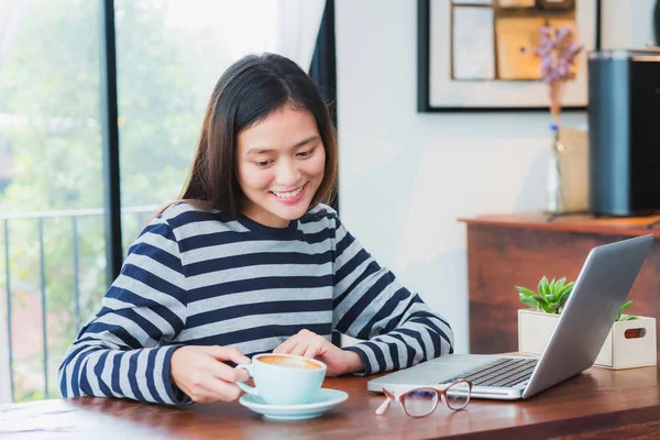 Asiatico donna prendere un pausa da utilizzando su computer portatile e bere — Foto Stock