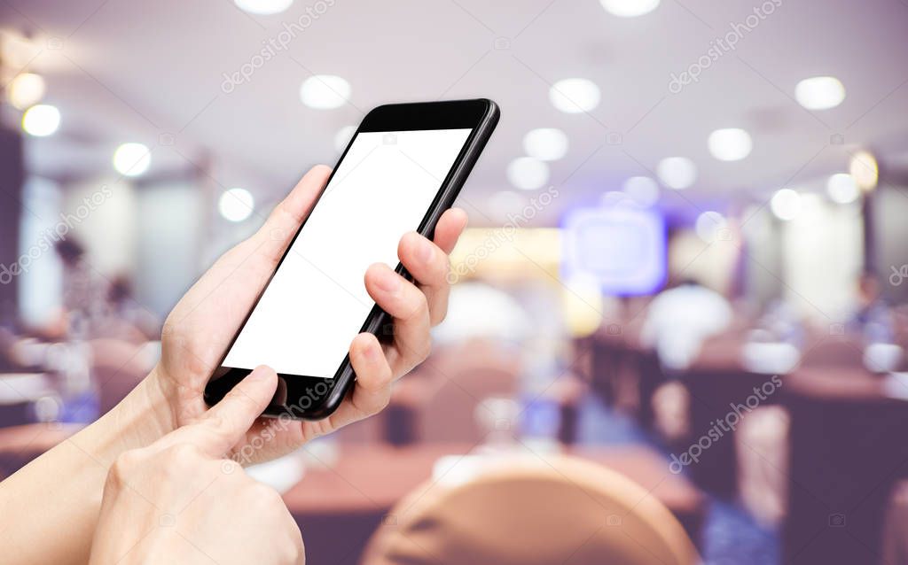 Hand click mobile phone with blur seminar hall room background b