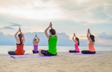 Yoga sınıf deniz Beach deki akşam günbatımı, bir grup insan yapıyor