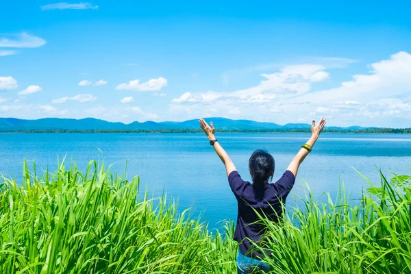 Happy young traveler woman raised arm up to sky enjoying a beaut