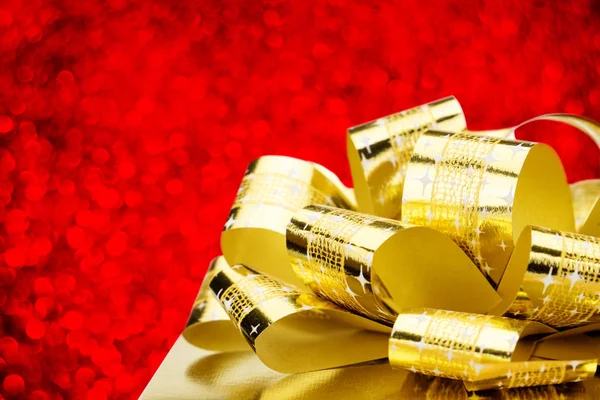 Fermer Boîte cadeau dorée avec grand arc au bokeh white blur bac — Photo