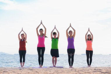 Yoga sınıf deniz sahilinde akşam, bir grup insan namast yapıyor