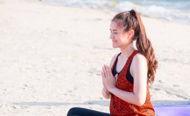 Asyalı kadın oturmuş el Mudra yapıyor yoga poz coastli, kum üzerinde