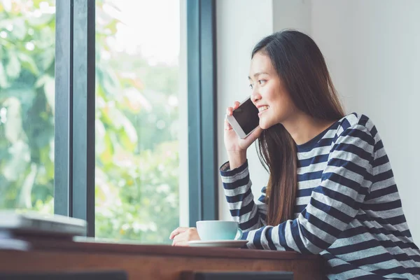 Cep telefonu üzerinde konuşurken ve kafe restaura oturan Asyalı kadın
