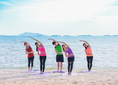 Yoga sınıf deniz sahilinde akşam, bir grup insan Standi yapıyor