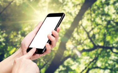 Park arka plan bulanıklık yeşil ağaca ile el tıklayın cep telefonu 