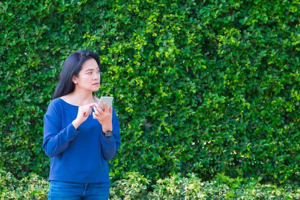 Asian woman in causal cloth and smile while use mobile phone out