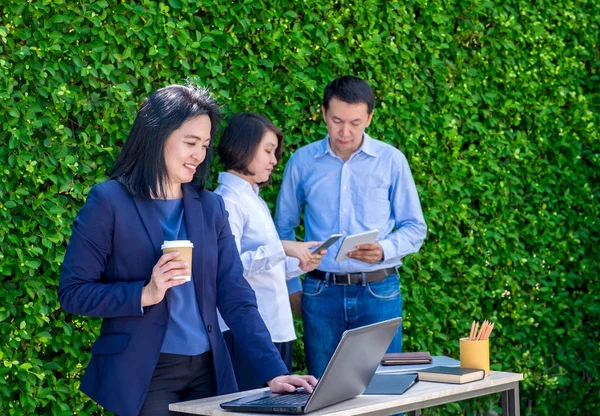 Affärskvinna som arbetar utanför kontoret med teamet på grönt blad wal — Stockfoto