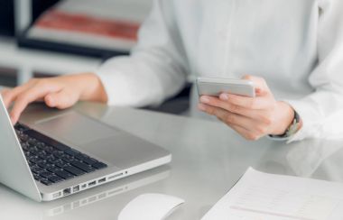 Cep telefonu tutan ve dizüstü bilgisayar kullanarak bir işkadını yakın com