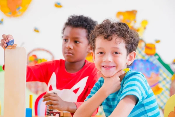 Los estudiantes de Kindergarten sonríen cuando juegan al juguete en la sala de juegos en pres —  Fotos de Stock