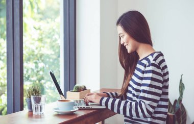 Asyalı kadın café restaur pencerede yakınındaki dizüstü bilgisayarda kullanma