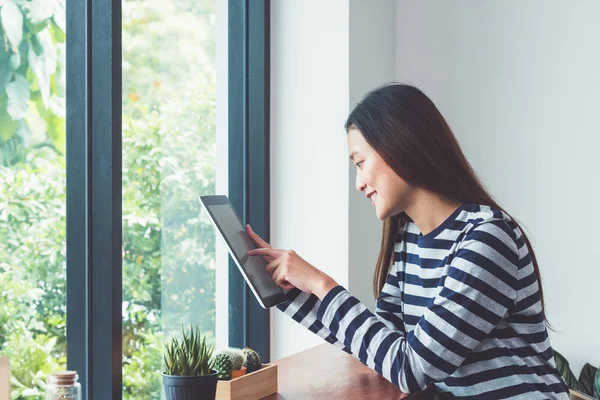 Asiatico donna utilizzando su tablet computer vicino finestra a caffè restaur — Foto Stock