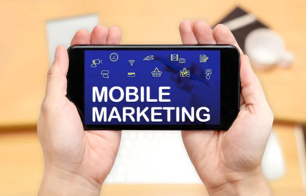 Guardando due mani che tengono il telefono cellulare con Mobile marketing wor — Foto Stock