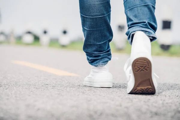 Close up woman wear jean and white sneaker walking forward on hi