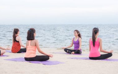 Yoga sınıf deniz Beach deki akşam günbatımı, grup Asya insan 