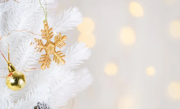 Gold snowflake and decor ball hanging on white Christmas tree wi — Stock Photo, Image