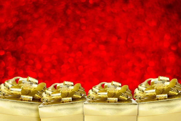 Close up gruppo di scatola regalo d'oro con grande fiocco a bokeh rosso sfocatura — Foto Stock